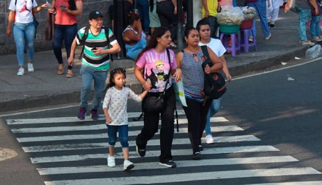 Adultos que cruzan la calle con niños respetan los semáforos y sendas peatonales